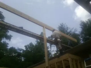Carpenter setting a ridge beam over a new addition frame — Ice Dam Removal by Roofing Brothers in Cressey