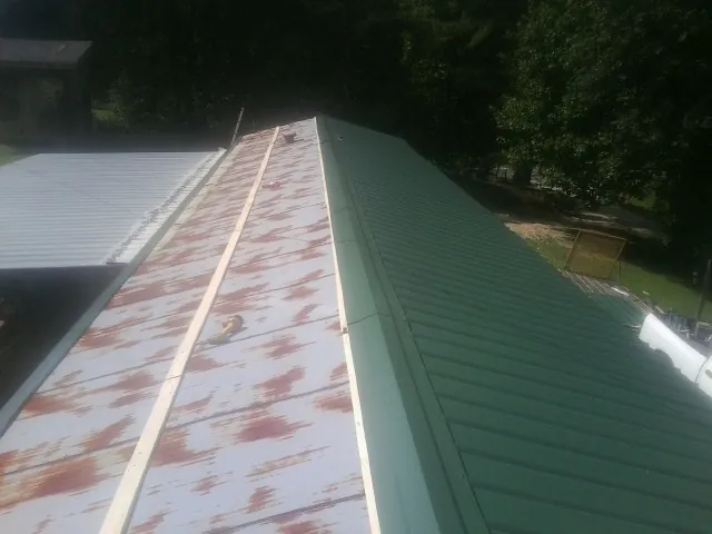 Old rusted panels beside newly installed green metal roofing — Wind Damage Roof Repair by Roofing Brothers in Cressey