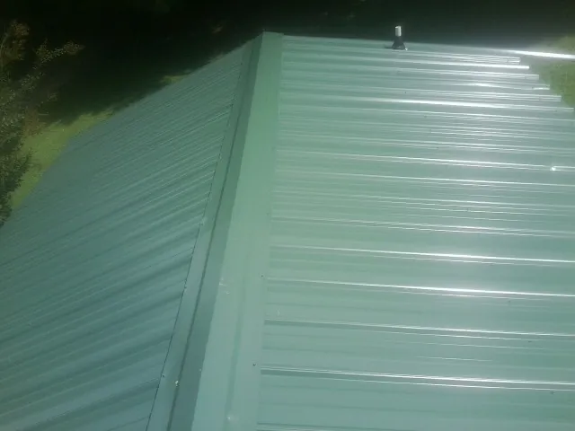 New green metal panels meeting at the ridge of a roof — Flat Roof Repair work by our crew in Cressey
