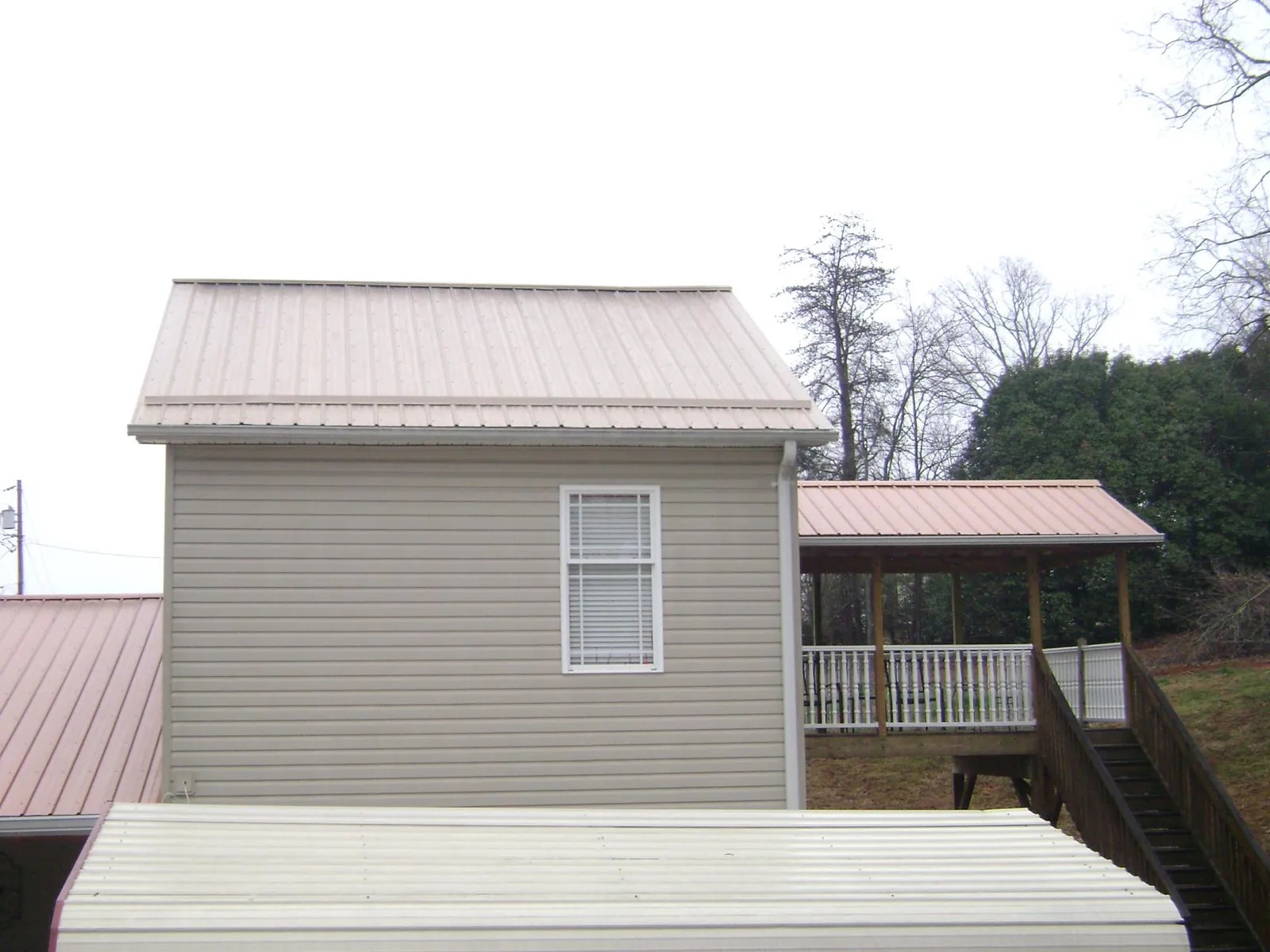 Tan metal roofs on a two story addition and attached porch, from a Roof Replacement job in Cressey
