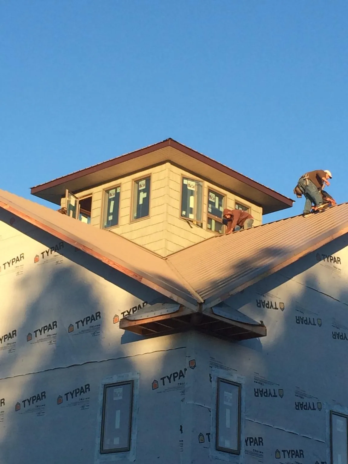 Roofers working around a rooftop cupola on a new metal roof at sunset — Roof Waterproofing in Cressey by Roofing Brothers